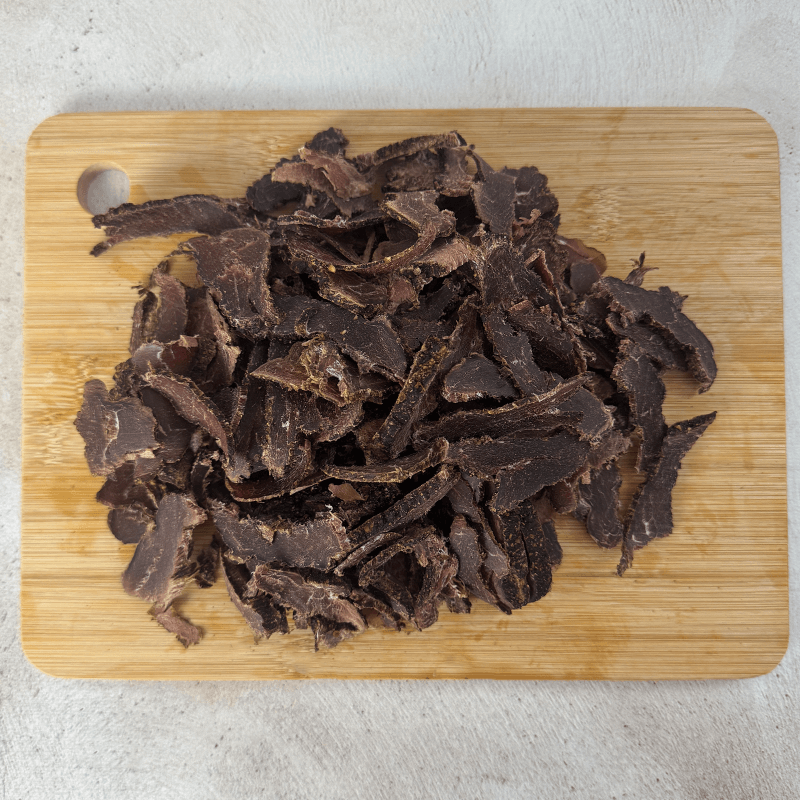 Dried springbok biltong on a wooden cutting board