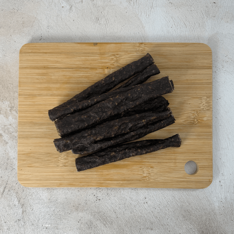 a pile of springbok droewors laying on a wood board with an top angle shot of the product