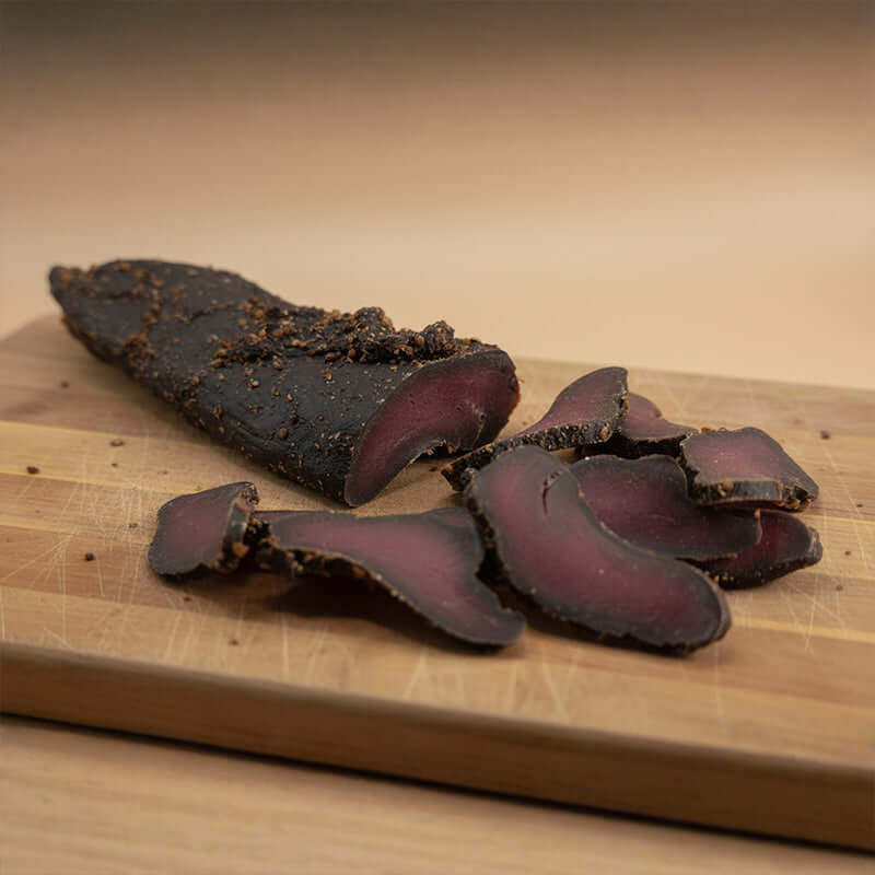 Kudu Biltong - Game Biltong slices and whole piece on wooden cutting board.