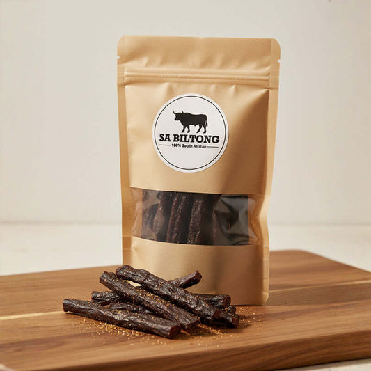 Kudu Droëwors packed in a gold-coated bag with pieces placed on a wooden board.