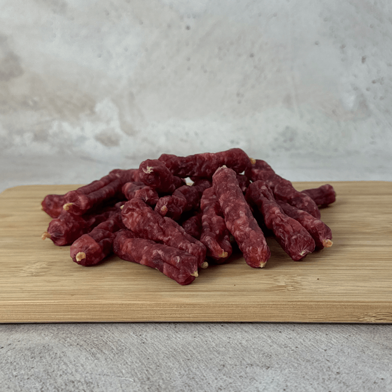 salami bites on a wooden cutting board with a light background with a front angle shot