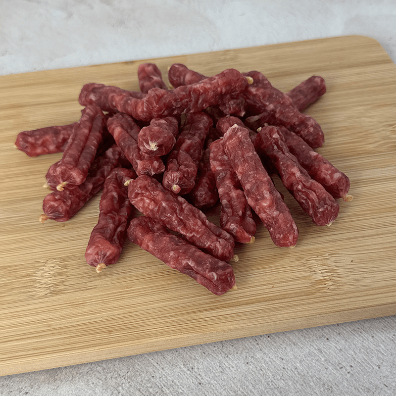 salami bites on a wooden cutting board with a light background