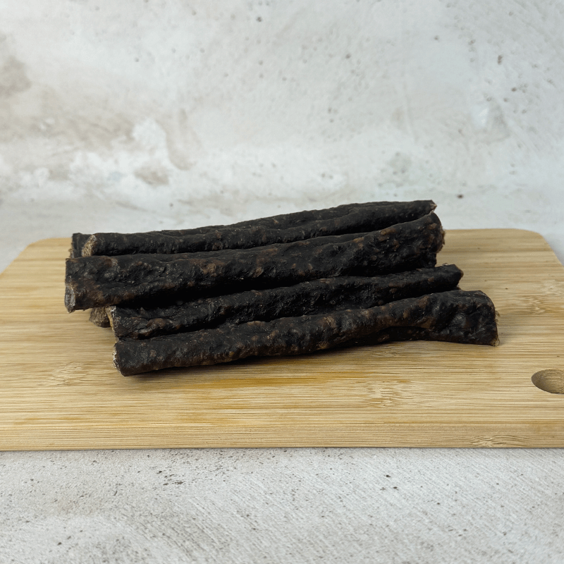a pile of springbok droewors laying on a wood board with an front angle shot of the product
