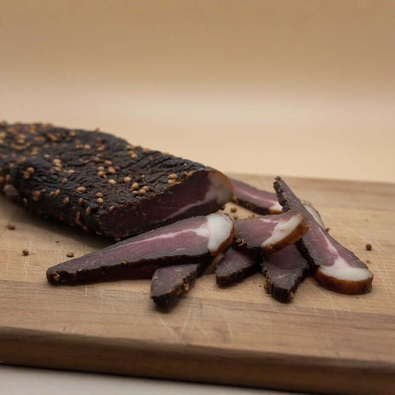 Freshly sliced biltong from a whole biltong piece, showing tender texture and traditional South African seasoning